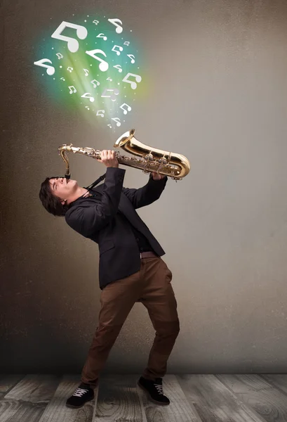 Jonge musicus spelen op saxofoon terwijl muzieknoten explodin — Stockfoto