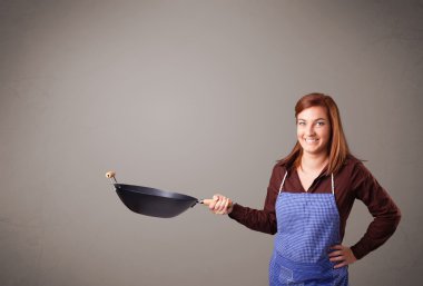 Genç bayan elinde kızartma tavası tutuyor.