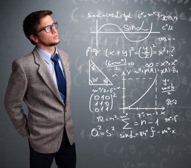 Karmaşık matematiksel işaretleri düşünen yakışıklı okul çocuğu.