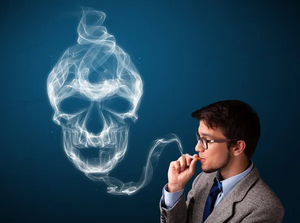 Young man smoking dangerous cigarette with toxic skull smoke — Stock Photo, Image