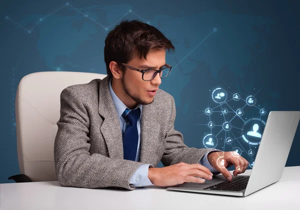 Young man sitting at desk and typing on laptop with social netwo — Stock Photo, Image