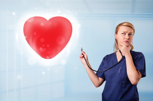 Young nurse healing a red heart — Stock Photo, Image