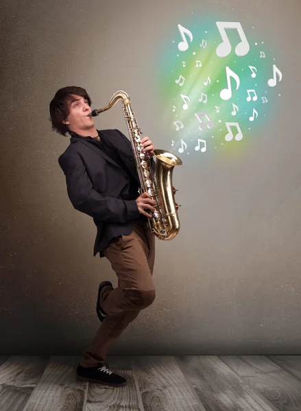 Jeune musicien jouant sur saxophone tandis que les notes de musique explosent — Photo