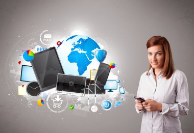 Genç bir kadın ayakta ve telefonunda geziniyor.