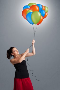 Genç bir kadın elinde renkli balonlar tutuyor.