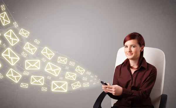 Atractiva jovencita sosteniendo un teléfono con iconos de mensaje — Foto de Stock