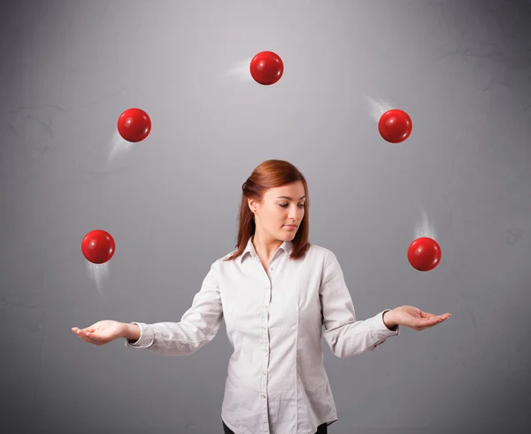 Młoda dziewczyna stoi i żonglerka z czerwonymi kulkami — Zdjęcie stockowe