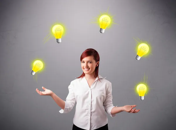 Young lady standing and juggling with light bulbs — Stock Photo, Image