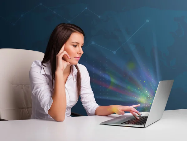 Beautiful woman sitting at desk and typing on laptop with abstra — Stock Photo, Image