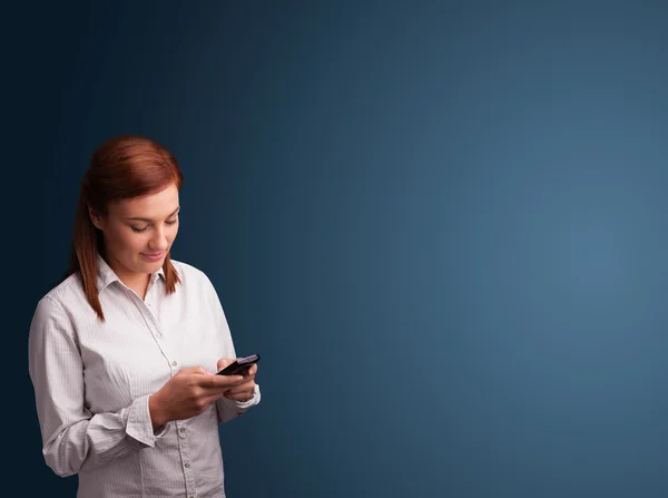 Mujer joven de pie y escribiendo en su teléfono con espacio para copiar —  Fotos de Stock