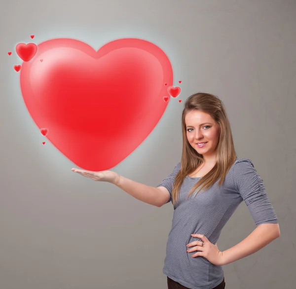 Genç bir bayan 3 boyutlu kırmızı bir kalp taşıyor. — Stok fotoğraf