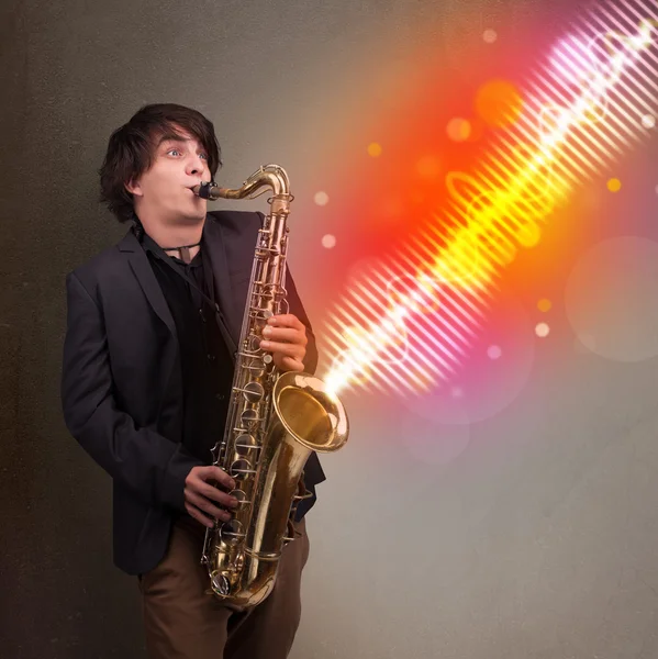 Young man playing on saxophone with colorful sound waves — Stock Photo, Image