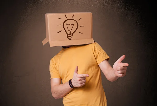 Jonge man gebaren met een kartonnen doos op zijn hoofd met licht — Stockfoto