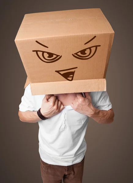 Young man gesturing with a cardboard box on his head with evil f — Stock Photo, Image