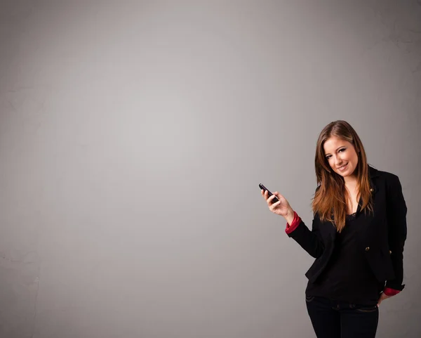 Young lady standing and holding a phone with copy space — Stock Photo, Image