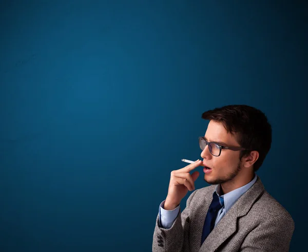 Молодой человек курит сигарету с копировальным местом — стоковое фото