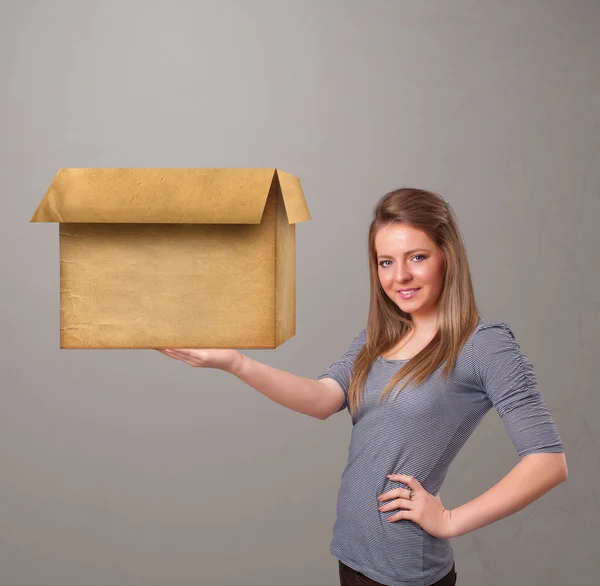 Mujer joven sosteniendo una caja de cartón vacía — Foto de Stock