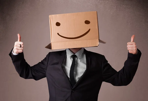 Бизнесмен жестикулирует с картонной коробкой на голове с улыбкой — стоковое фото