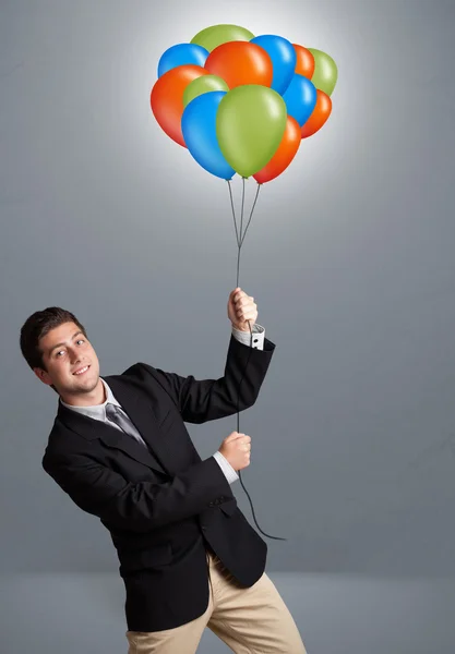 Hezký muž drží barevné balónky — Stock fotografie