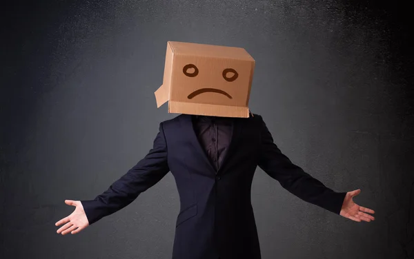 Giovane uomo con una scatola di cartone marrone sulla testa con la faccia triste — Foto Stock