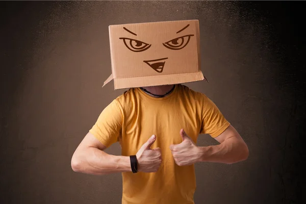 Young man gesturing with a cardboard box on his head with evil f — Stock Photo, Image