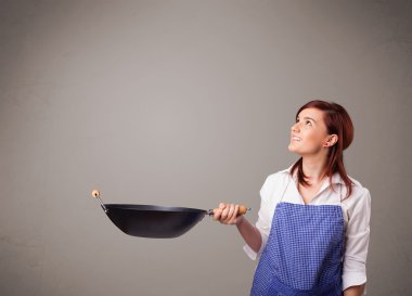 Genç bayan elinde kızartma tavası tutuyor.