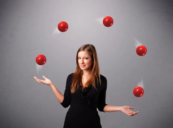 Joven chica de pie y malabarismo con bolas rojas — Foto de Stock