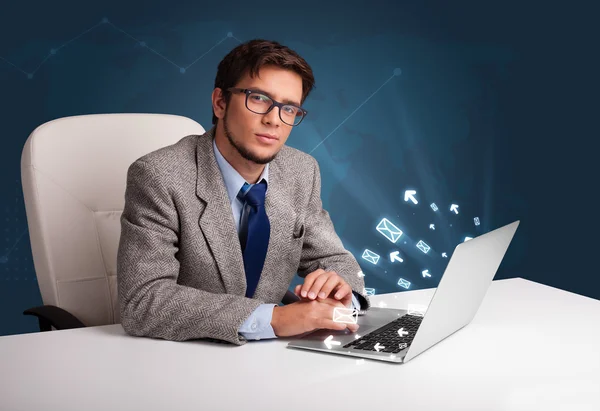 Young man sitting at dest and typing on laptop with message icon — Stock Photo, Image