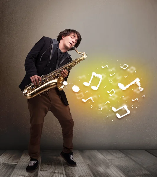 Knappe muzikant die op saxofoon speelt met muzikale noten — Stockfoto