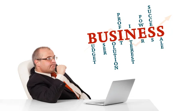 Bisinessman sitter vid skrivbord och ser laptop med business wor — Stockfoto