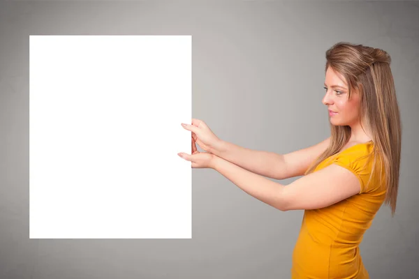 Mujer joven que presenta espacio de copia de papel blanco — Foto de Stock