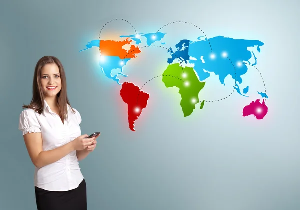 Young woman holding a phone and presenting colorful world map — Stock Photo, Image