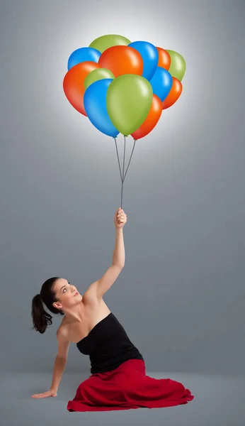 Νεαρή γυναίκα που κρατά πολύχρωμα μπαλόνια — Φωτογραφία Αρχείου