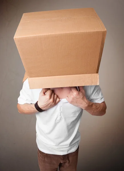 Mladý muž gestikuluje s lepenkovou krabicí na hlavě — Stock fotografie