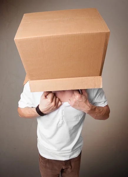 Jeune homme gesticulant avec une boîte en carton sur la tête — Photo