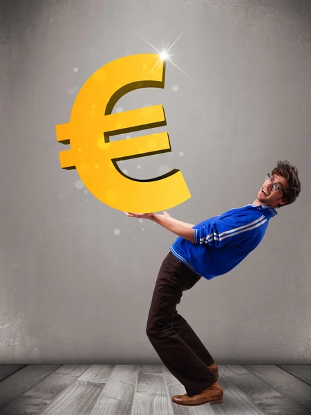 Good-looking boy holding a big 3d gold euro sign — Stock Photo, Image