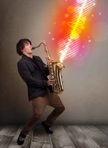 Young man playing on saxophone with colorful sound waves — Stock Photo, Image