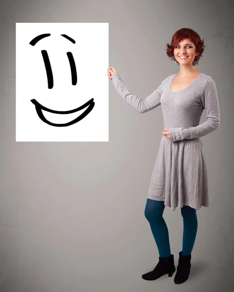 Joven mujer sosteniendo sonriente cara dibujo — Foto de Stock