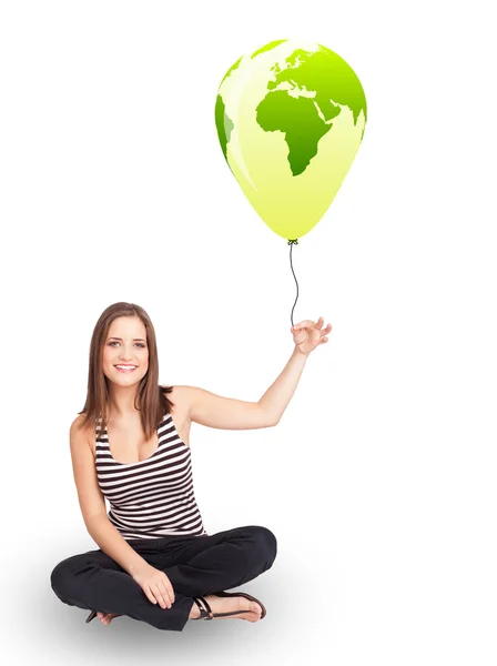 Happy lady holding a green globe balloon — Stock Photo, Image