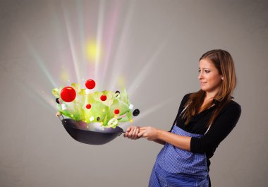 Genç bir kadın taze sebze pişiriyor.