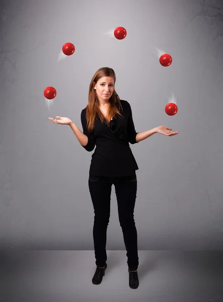 Joven chica de pie y malabarismo con bolas rojas — Foto de Stock