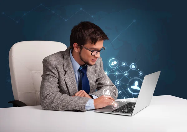 Young man sitting at desk and typing on laptop with social netwo — Stock Photo, Image