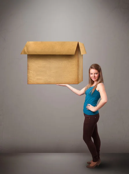 Mujer joven sosteniendo una caja de cartón vacía — Foto de Stock