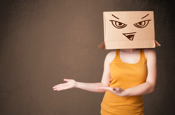 Young woman gesturing with a cardboard box on her head with evil — Stock Photo, Image