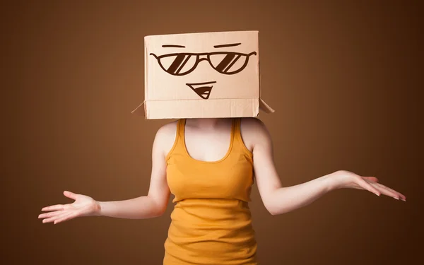 Jeune femme gestuelle avec une boîte en carton sur la tête avec le sourire — Photo