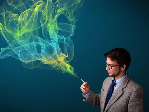 Handsome man smoking cigarette with colorful smoke — Stock Photo, Image