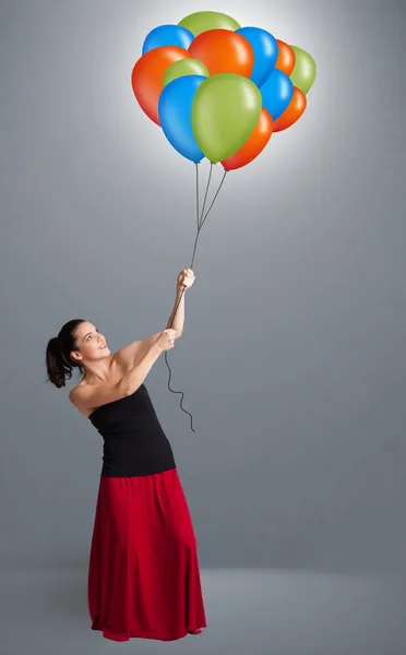 Ung kvinna som håller färgglada ballonger — Stockfoto