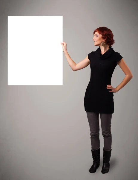 Jonge vrouw presenteren wit papier kopiëren ruimte — Stockfoto