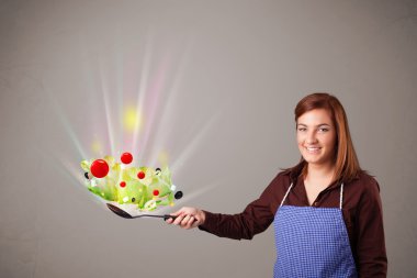 Genç bir kadın taze sebze pişiriyor.