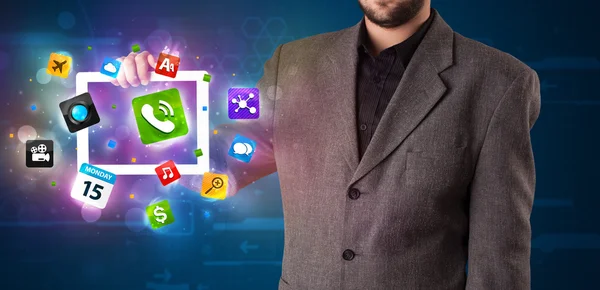 Zakenman die een tablet vasthoudt met moderne kleurrijke apps en pictogrammen — Stockfoto